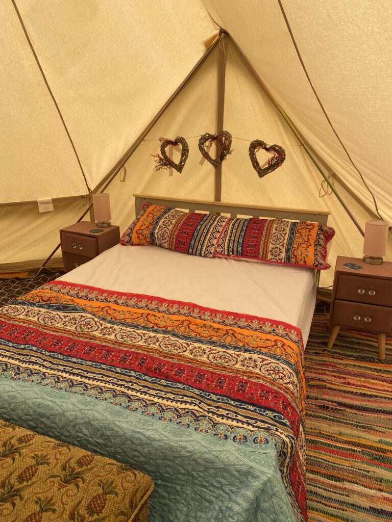 Double bed with colourful covers and a heart garland header