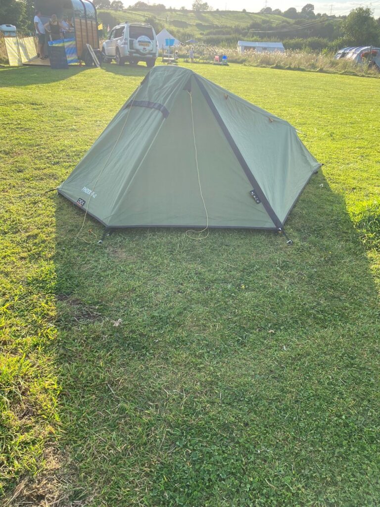 A small green tent surrounded by gree