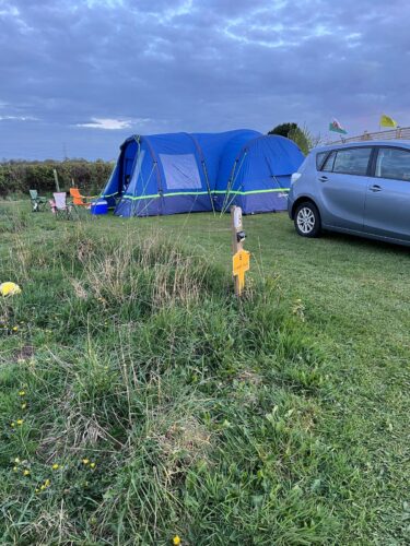 A blue tent is set up on a fully serviced pitch